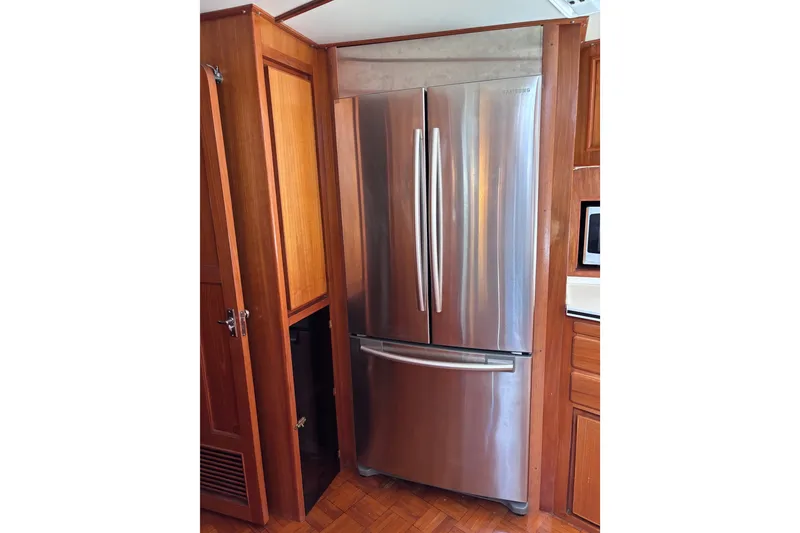 Slide: The Image of Stainless steel refrigerator in a 1991 Kha Shing Motoryacht kitchen with wooden cabinetry. - 24