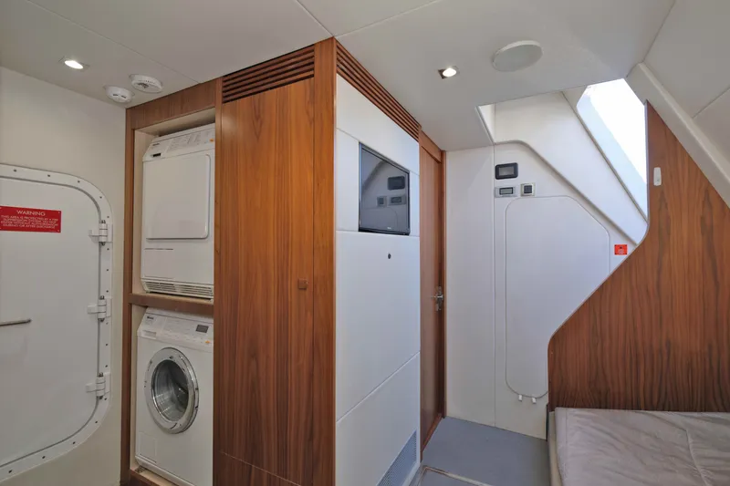 Slide: The Image of Laundry area inside 2018 Sunseeker 76 Yacht, featuring stacked washer and dryer units. - 82