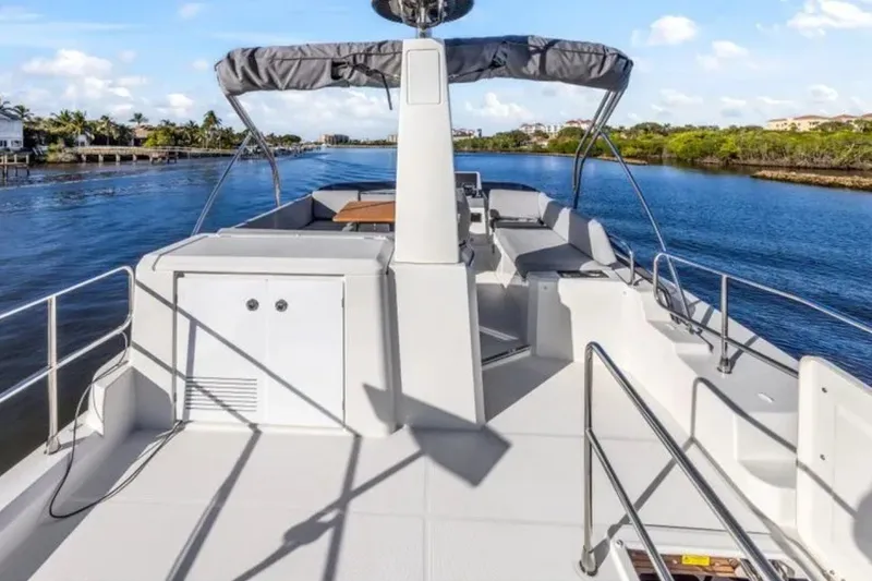 Slide: The Image of 2024 Beneteau Swift Trawler 41 Fly on serene waterway, showcasing spacious deck and sleek design. - 18