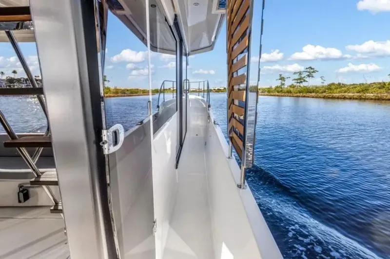 Slide: The Image of 2024 Beneteau Swift Trawler 41 Fly cruising on a serene waterway under a clear blue sky. - 12