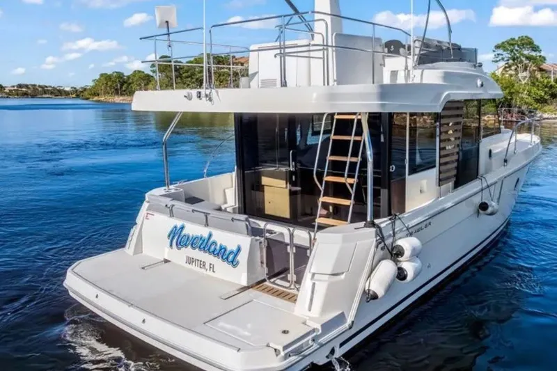 Slide: The Image of 2024 Beneteau Swift Trawler 41 Fly on serene water, rear view with ladder and nameplate. - 6
