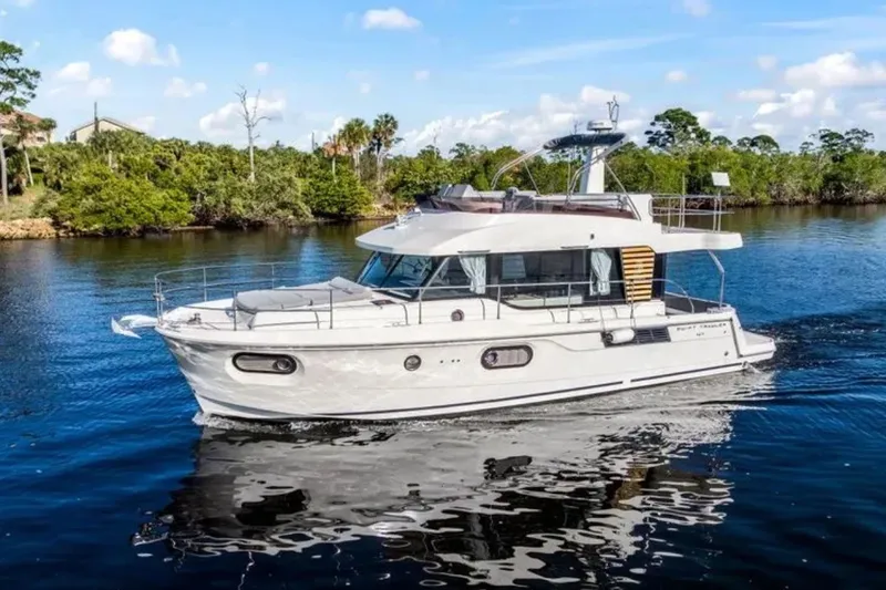 The Image of 2024 Beneteau Swift Trawler 41 Fly cruising on a serene waterway, surrounded by lush greenery. - 0