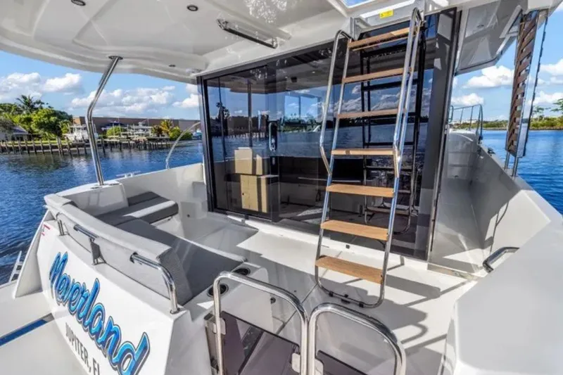 Slide: The Image of 2024 Beneteau Swift Trawler 41 Fly, spacious deck with seating and ladder, docked by water. - 7
