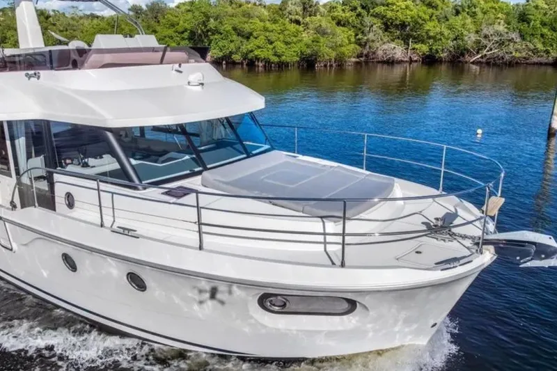 Slide: The Image of 2024 Beneteau Swift Trawler 41 Fly cruising on a serene river with lush greenery. - 5