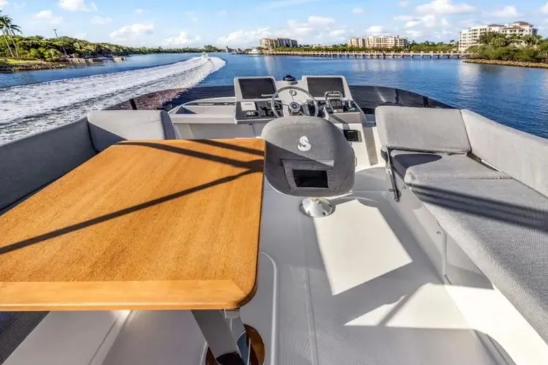 Slide: The Image of 2024 Beneteau Swift Trawler 41 Fly's flybridge with seating and table, cruising on a sunny day. - 21