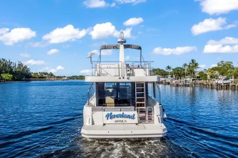 Slide: The Image of 2024 Beneteau Swift Trawler 41 Fly cruising on a scenic waterway under a clear blue sky. - 4