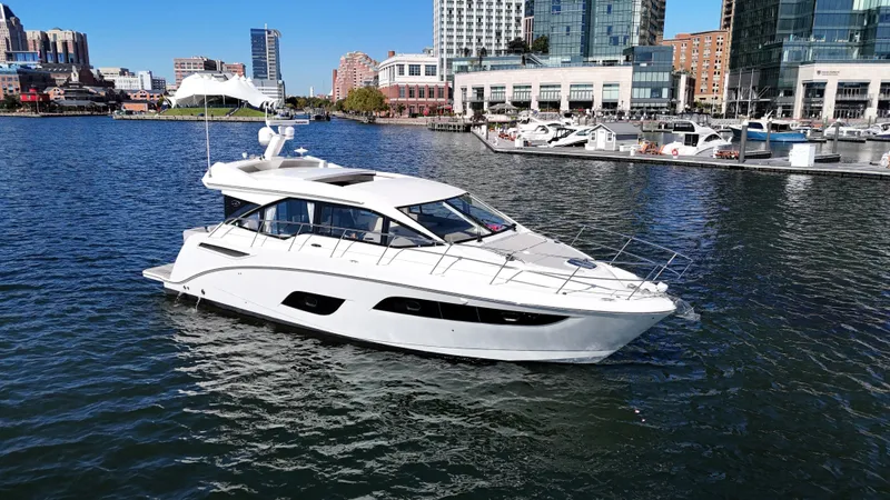 The Image of A sleek white motorboat anchored in an urban harbor, surrounded by modern buildings. - 0