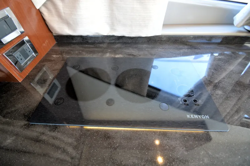 Slide: The Image of A sleek Kenyon cooktop on a glossy countertop in a 2018 Sea Ray 460 Express Cruiser. - 31