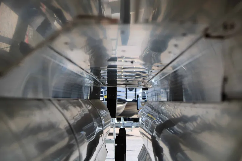 Slide: The Image of Close-up of the underside of a 2027 Bennington 25 QSBA Tri Toon, showing shiny aluminum tubes. - 26