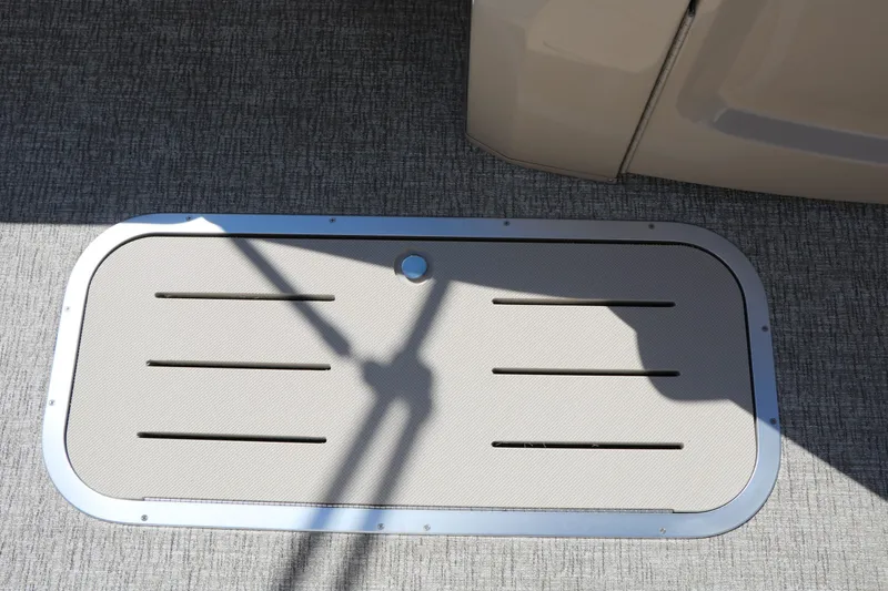 Slide: The Image of A rectangular floor hatch with slits on a gray carpeted surface. - 46
