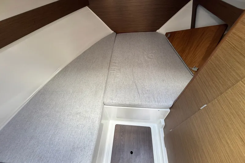Slide: The Image of 2022 Jeanneau NC 795 Series 2 cabin interior with cushioned berth and wooden accents. - 10