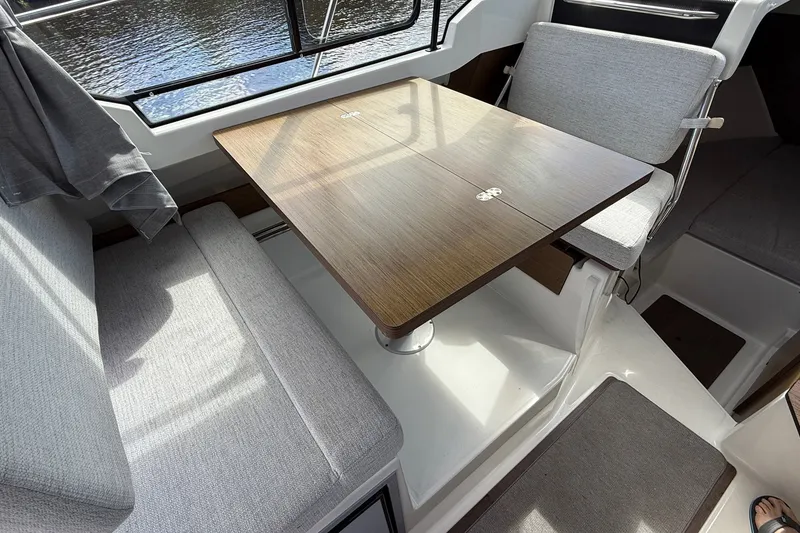 Slide: The Image of Interior of 2022 Jeanneau NC 795 Series 2 boat with wooden table and gray seating. - 15