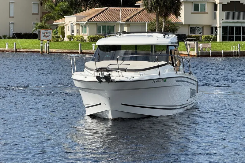 Slide: The Image of 2022 Jeanneau NC 795 Series 2 boat cruising on a calm residential waterway. - 2