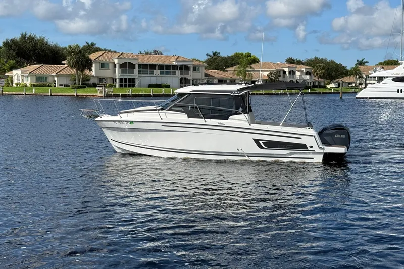 Slide: The Image of 2022 Jeanneau NC 795 Series 2 boat on calm water, with waterfront homes in the background. - 4