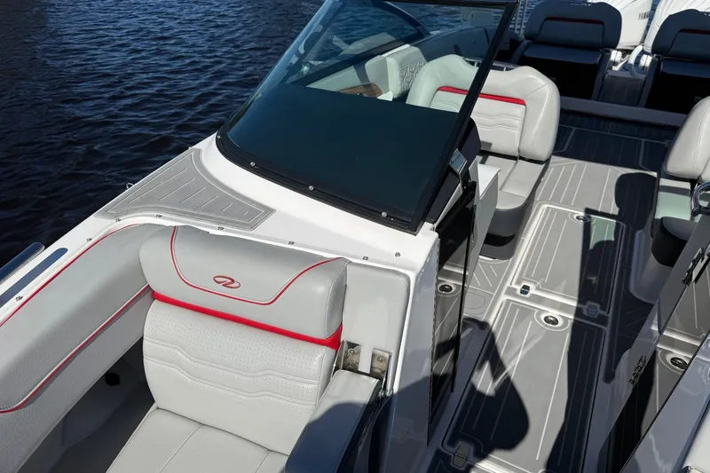 Slide: The Image of 2024 Regal LX9 boat interior with gray seating and red accents on the water. - 19