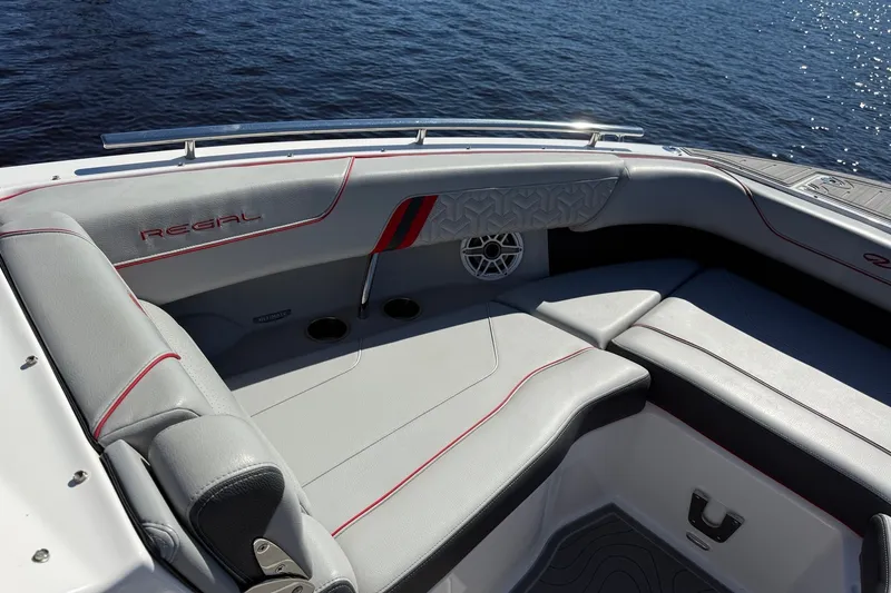 Slide: The Image of 2024 Regal LX9 boat interior with gray seating and red accents on a sunny day. - 15
