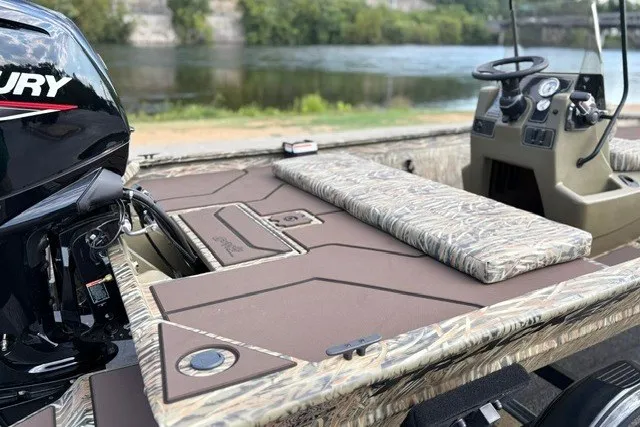 Slide: The Image of 2027 Tracker Grizzly 1860 CC boat with camo seating and Mercury engine by a river. - 15