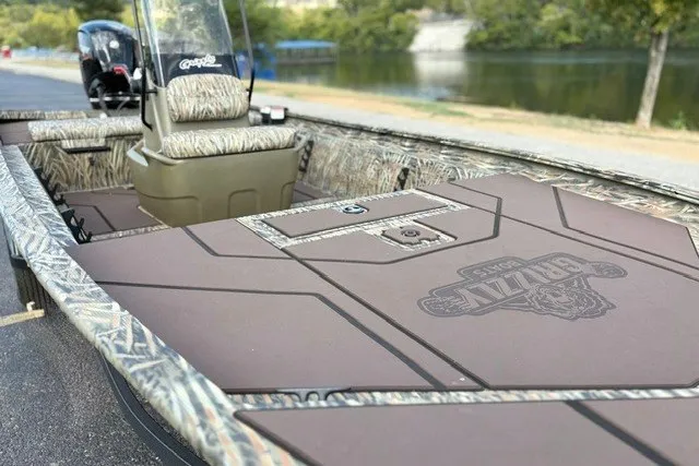Slide: The Image of 2027 Tracker Grizzly 1860 CC boat with camo design, spacious deck, and comfortable seating by a lake. - 14