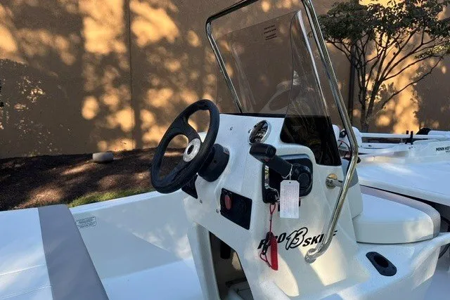 Slide: The Image of 2026 Mako Pro Skiff 13 CC boat console with steering wheel and windshield. - 8