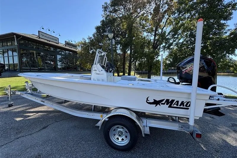Slide: The Image of 2026 Mako 18 Pro Skiff boat on trailer near a lake and building. - 9