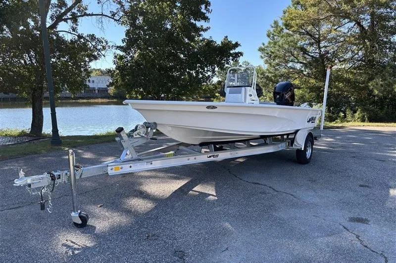 Slide: The Image of 2026 Mako 18 Pro Skiff on trailer by a lakeside, surrounded by trees. - 2