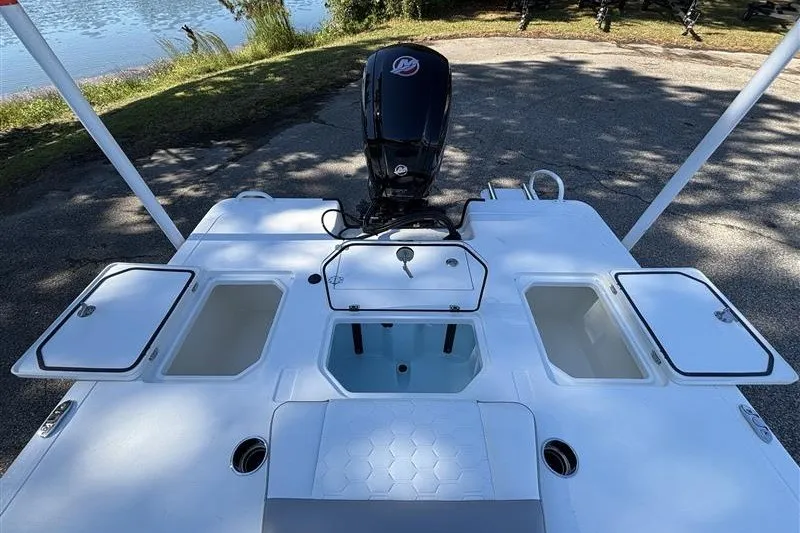 Slide: The Image of 2026 Mako 18 Pro Skiff boat with open storage compartments and motor, near a lake. - 21