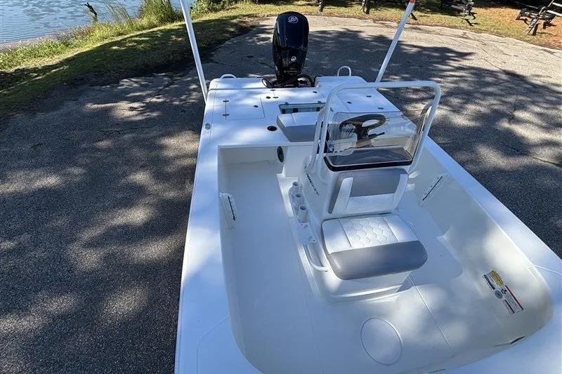 Slide: The Image of 2026 Mako 18 Pro Skiff boat with seating and steering console, parked near a lake. - 14