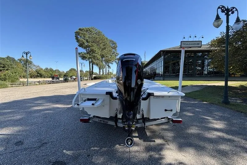 Slide: The Image of 2026 Mako 18 Pro Skiff boat with outboard motor, parked outdoors on a sunny day. - 7