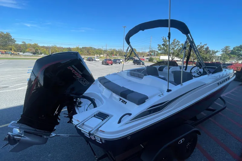 Slide: The Image of 2027 Tahoe T21 boat with outboard motor in a parking lot under clear blue sky. - 2