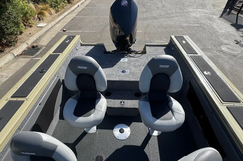 Slide: The Image of 2027 Tracker Targa V-19 WT boat interior with seating and motor, parked on pavement. - 13