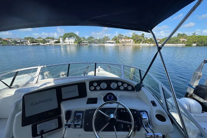 Slide: The Image of Cockpit view of 2002 Silverton 410 Sport Bridge with Garmin navigation, overlooking serene waterfront homes. - 15