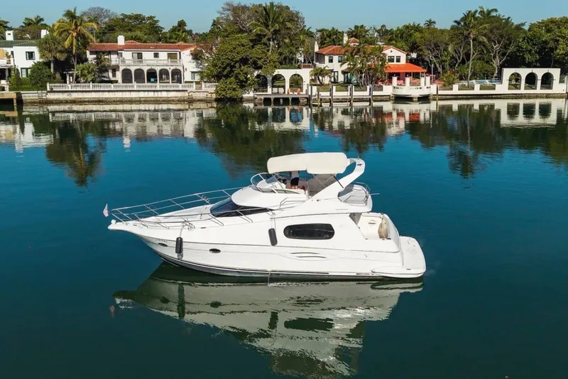 Slide: The Image of 2002 Silverton 410 Sport Bridge yacht cruising on a serene waterfront with luxury homes. - 3