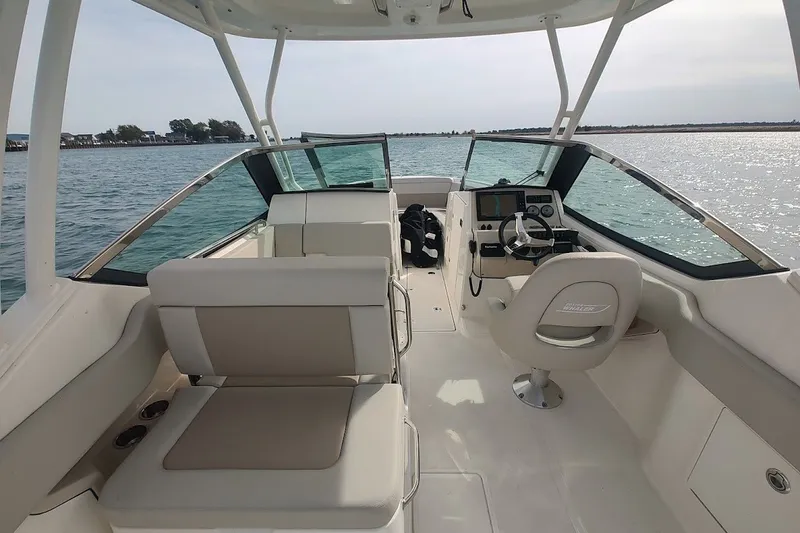 Slide: The Image of 2022 Boston Whaler 240 Vantage boat interior with helm and seating, on calm water. - 37