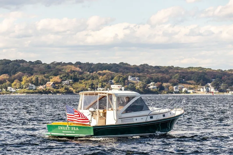 Slide: The Image of Little Harbor WhisperJet 38 boat from 2000 on scenic waterway with American flag. - 4