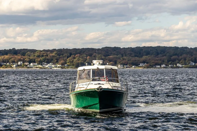 Slide: The Image of Little Harbor WhisperJet 38, 2000 model, cruising on a scenic lake with wooded shoreline. - 3