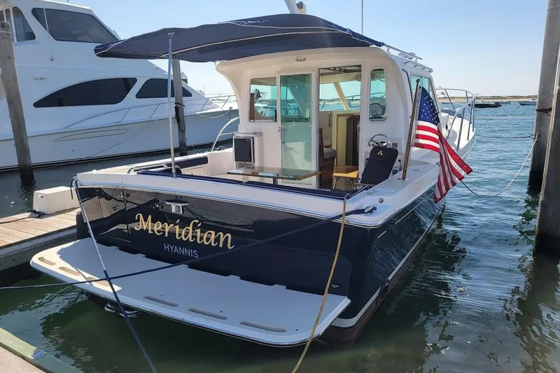 Slide: The Image of 2005 Compton 33 Downeast Express HT boat docked, featuring "Meridian" name and American flag. - 38