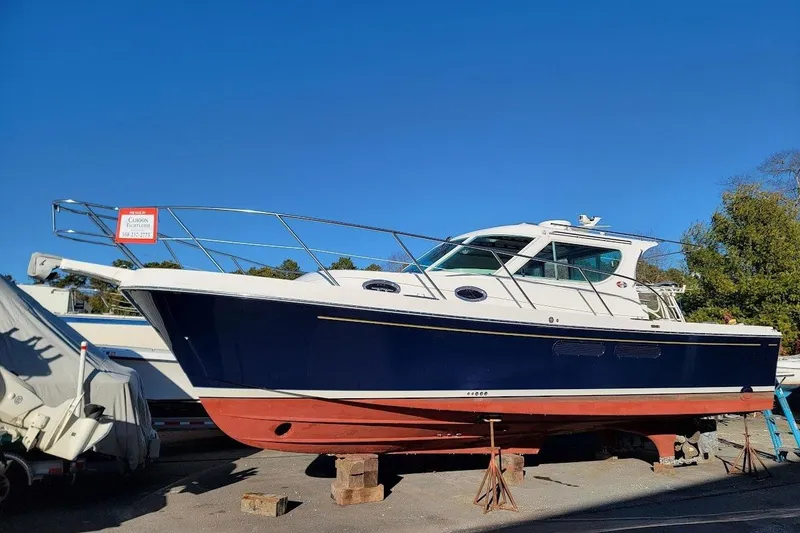 Slide: The Image of 2005 Compton 33 Downeast Express HT boat on stands, blue hull, clear sky background. - 33