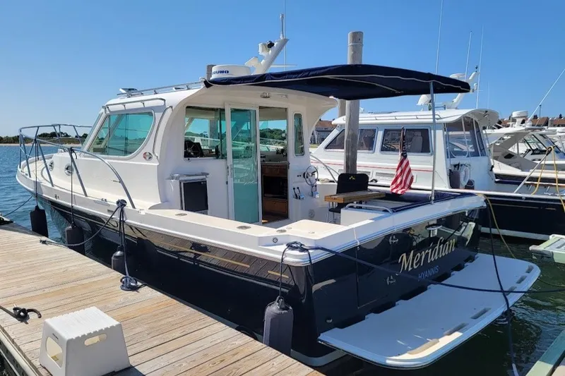 The Image of 2005 Compton 33 Downeast Express HT docked, featuring sleek design and American flag. - 0