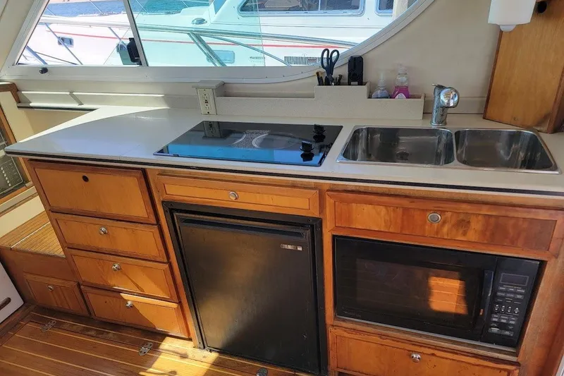 Slide: The Image of Compact kitchen area in a 2005 Compton 33 Downeast Express HT boat with stove, sink, and microwave. - 26