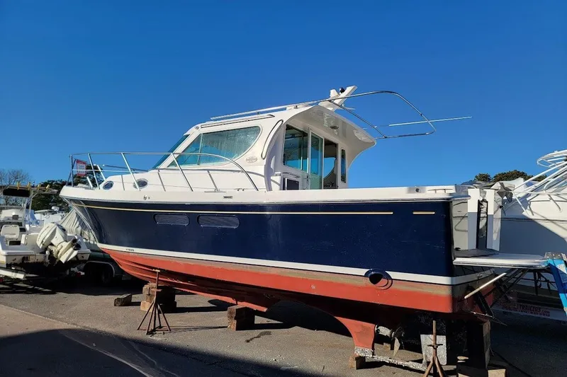 Slide: The Image of 2005 Compton 33 Downeast Express HT boat on stands, blue hull, sunny day. - 36