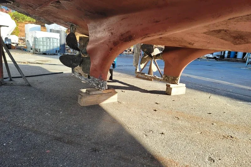 Slide: The Image of 2005 Compton 33 Downeast Express HT boat propellers on dry dock, supported by wooden blocks. - 35