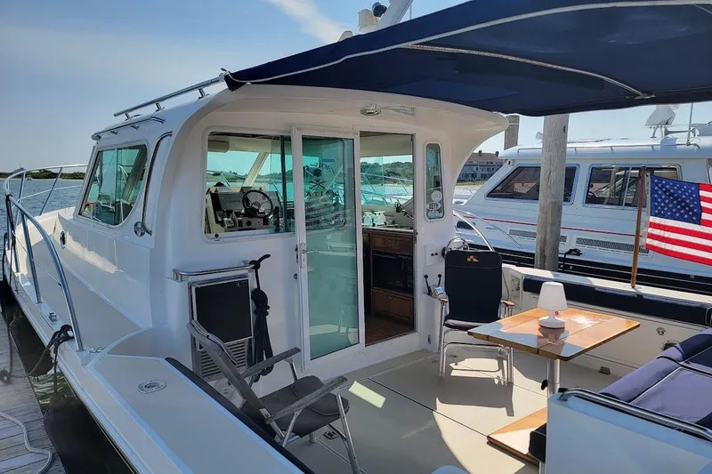 Slide: The Image of 2005 Compton 33 Downeast Express HT yacht docked, featuring outdoor seating and American flag. - 9