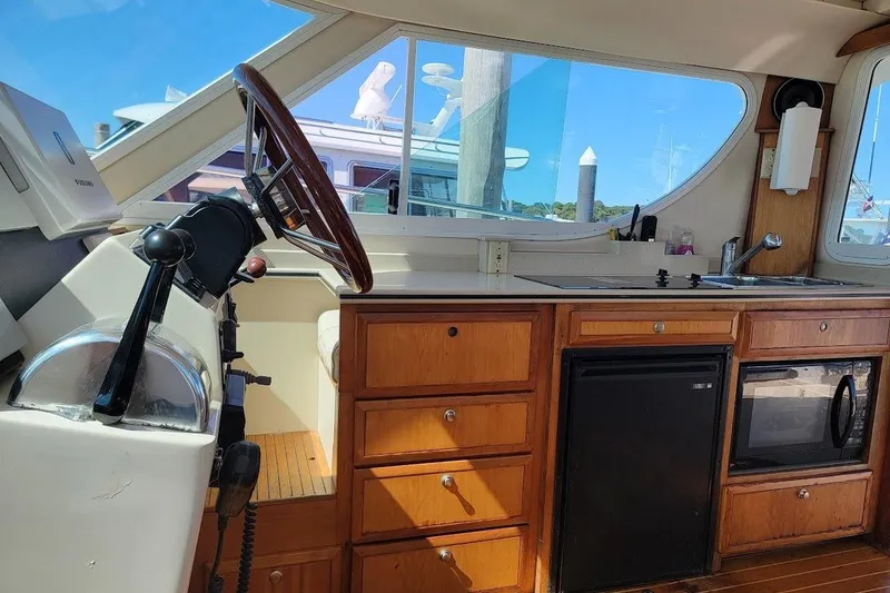 Slide: The Image of Interior of 2005 Compton 33 Downeast Express HT with helm, kitchenette, and wooden cabinetry. - 10