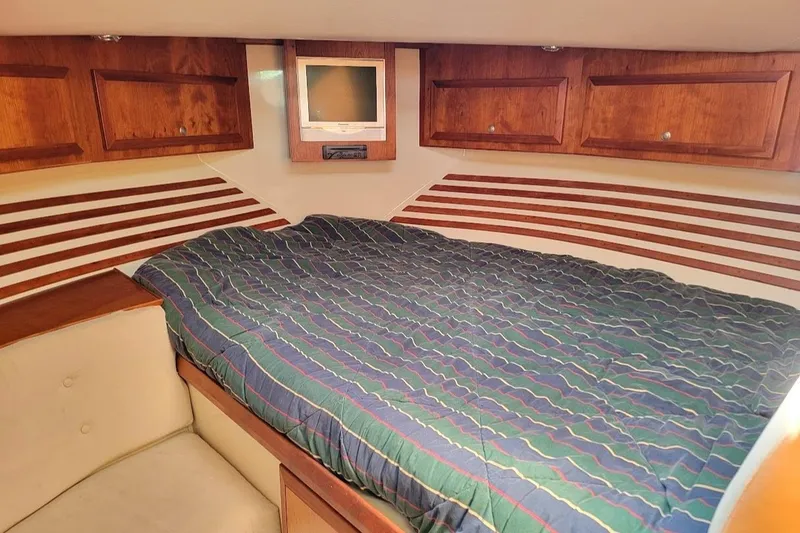 Slide: The Image of Cozy cabin interior of 2005 Compton 33 Downeast Express HT with wood cabinets and striped bedding. - 11