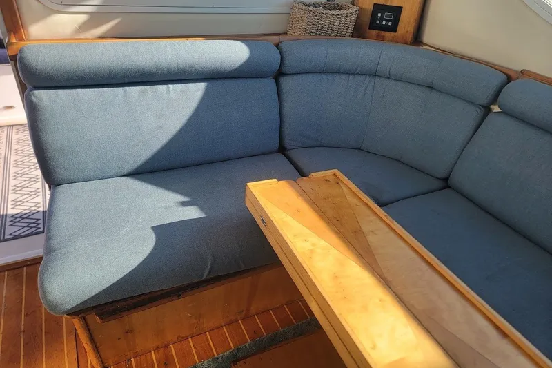 Slide: The Image of Interior seating of 2005 Compton 33 Downeast Express HT with blue cushions and wooden table. - 17