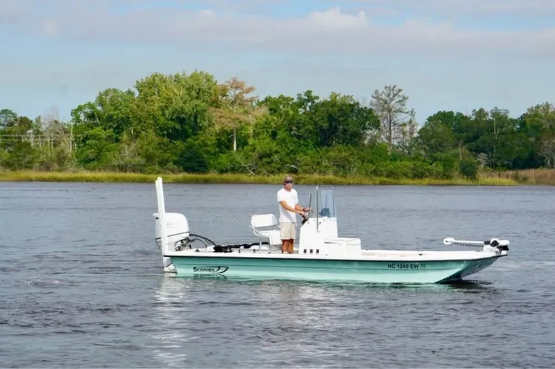 The Image of 2021 Carolina Skimmer CS 21 boat on a calm river with lush green background. - 0