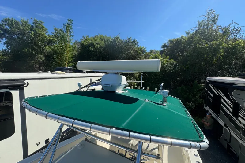 Slide: The Image of 2001 Pursuit 3070 Center Console boat with green canopy and radar, parked outdoors. - 59