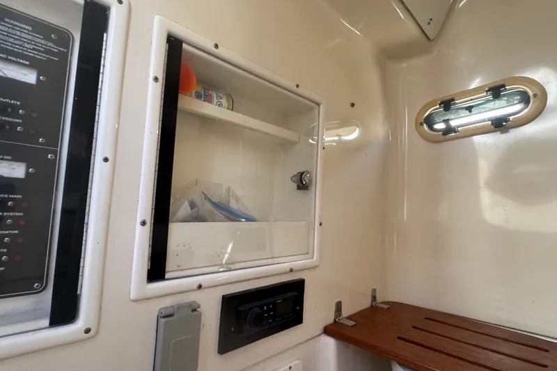 Slide: The Image of 2001 Pursuit 3070 Center Console interior with storage, control panel, and porthole window. - 38