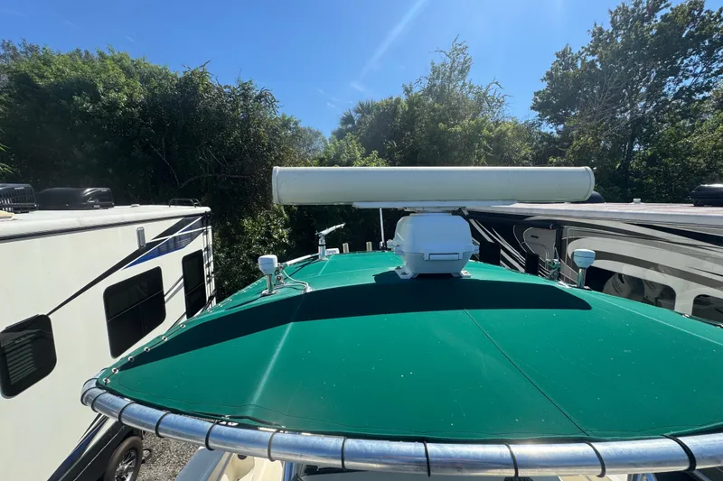 Slide: The Image of 2001 Pursuit 3070 Center Console boat with green canopy and radar, parked near RVs. - 58