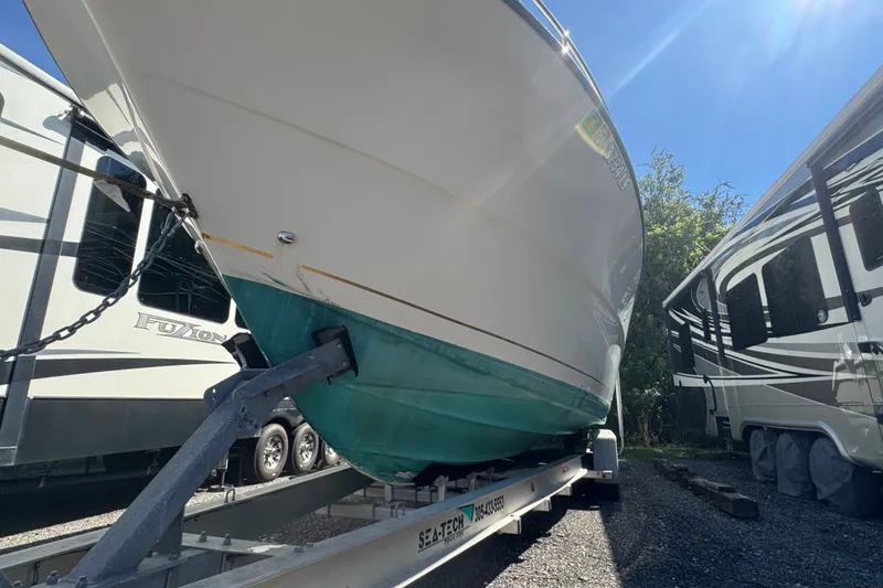 Slide: The Image of 2001 Pursuit 3070 Center Console boat on trailer, parked between RVs under clear sky. - 69